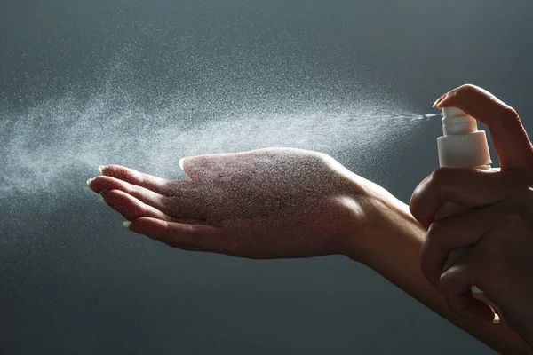 Közelkép az emberi kézről és a fertőtlenítő spray palackról sötét háttérrel. Kézfertőtlenítés. A coronavirus járványvédelmi megelőző intézkedései — Stock Fotó