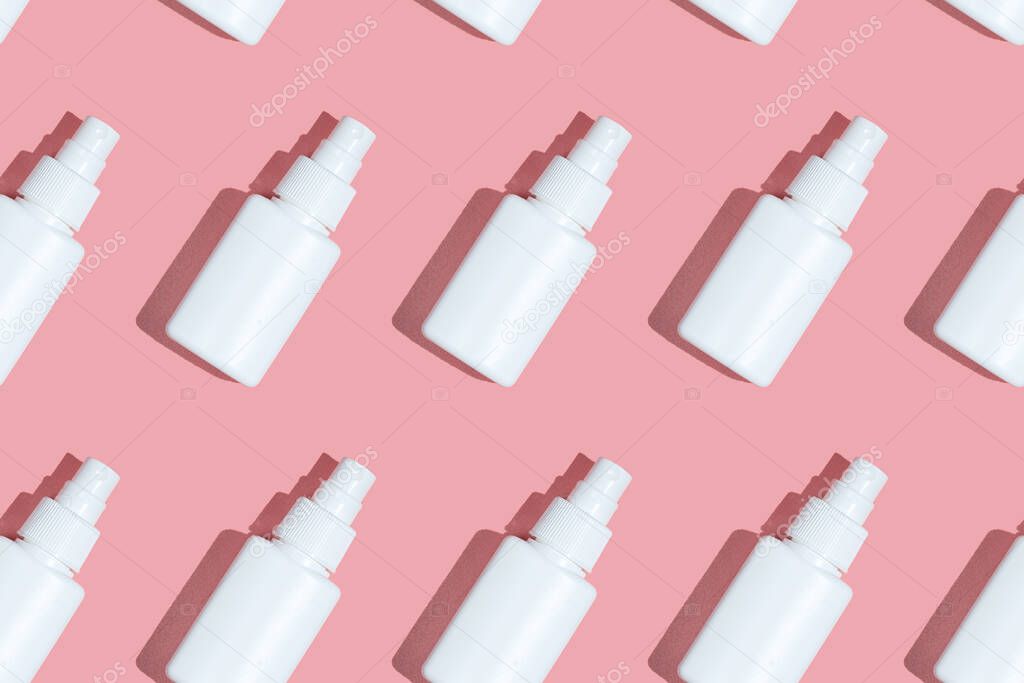 Regular Pattern of spray sanitizer tubes on the pink table flat lay. Fabric medical production, epidemic concept
