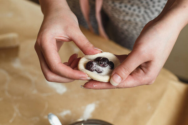 Cooking homemade dumplings, female hands sculpting dumpling closeup