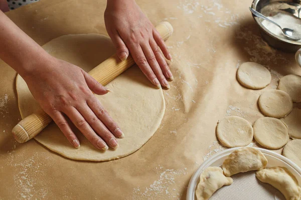 Женщина руками выкатывает тесто в муке со скалкой на домашней кухне — стоковое фото