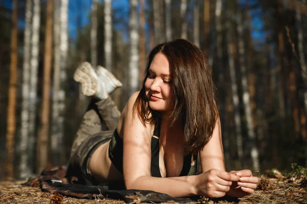 Женщина-туристка лежит на загорелом лесном лугу и наслаждается отдыхом. Камуфляж . — стоковое фото
