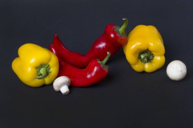 Karanlık bir arka plan üzerinde mantar ile sarı ve kırmızı biber. Biber ve mantar karanlık bir arka plan üzerinde kompozisyon.