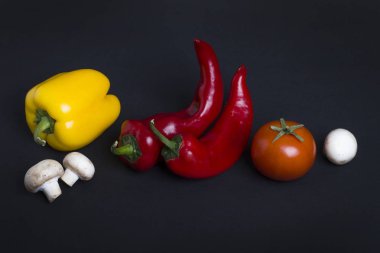 Sarı ve kırmızı biber domates karanlık bir arka plan ile. Biber ve domates siyah zemin bileşimi.