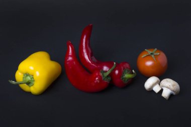 Sarı ve kırmızı biber domates karanlık bir arka plan ile. Biber ve domates siyah zemin bileşimi.