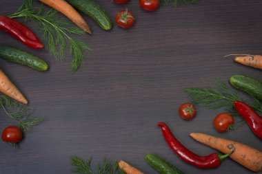 Sebze ahşap kahverengi zemin kavramı. Yeşil salatalık ve domates ahşap bir masa üzerinde. Havuç ve yeşillikleri ile kırmızı biber.