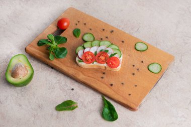 Salatalık, avokado ve domatesli ev yapımı kremalı vejetaryen sandviçler. Tahta kesme tahtasının üzerinde.