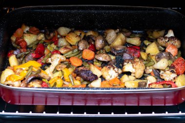 Pişmiş sebzeler kırmızı bir tepside.