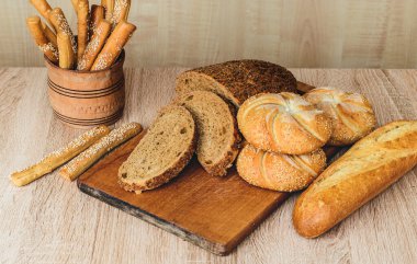 Çörekli çıtır ekmek. Fransız ekmeği. Taze taze ekmek. Ekmek arkaplanı. Ahşap arka planda farklı cins..