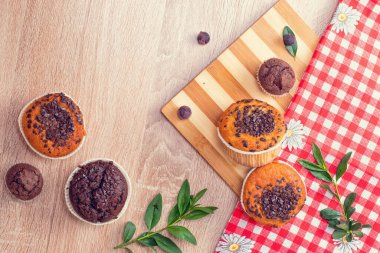 Çikolatalı kek ve fındıklı kek, arka planda ev yapımı fırın. Ahşap bir masada yaban mersinli kek. Tahtada taze böğürtlen ve tatlı börek var..