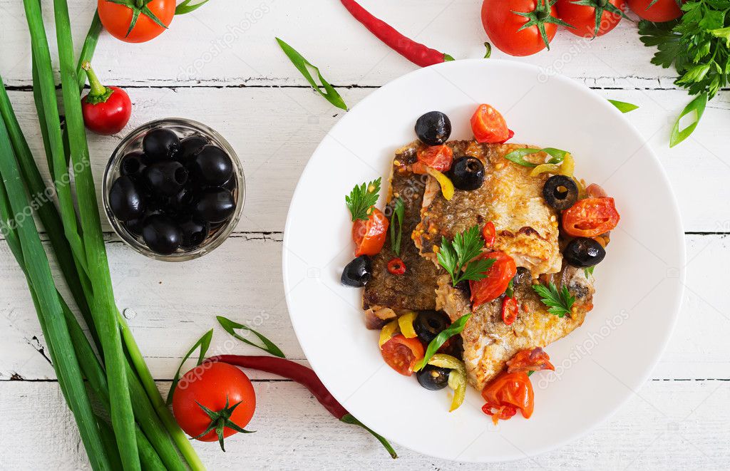 Fried hake fillet with tomato and olives