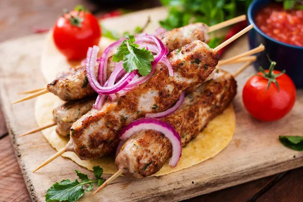 Lula kebab with vegetables on cutting board