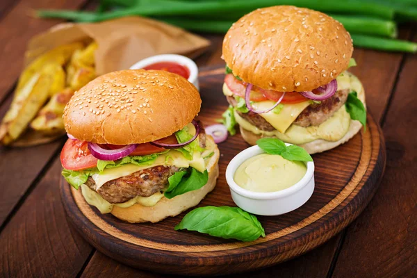 Dva hovězí hamburgery na dřevěné desce — Stock fotografie