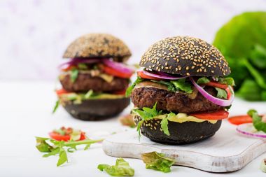 beyaz kesme tahtası üzerinde siyah hamburger
