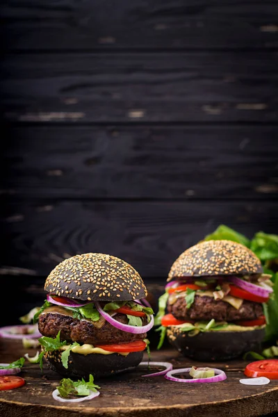 Hamburguesas negras en la tabla de cortar —  Fotos de Stock