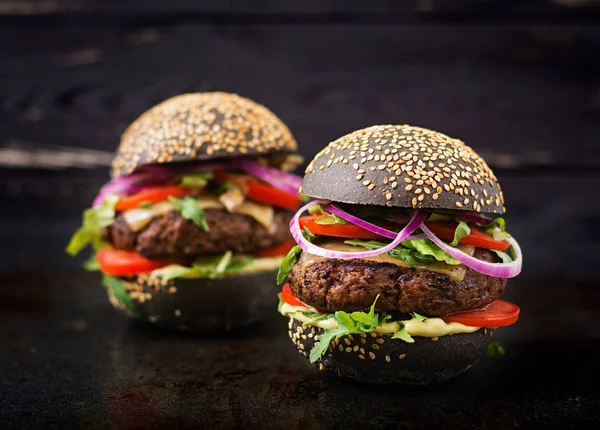 Hamburger neri su sfondo nero — Foto Stock