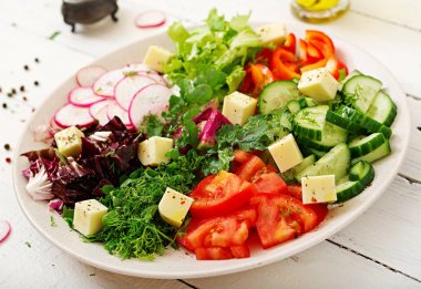 Ahşap masa üzerinde beyaz kase taze sebze ve yeşil ot salatası mix 