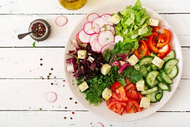 Ahşap masa üzerinde beyaz kase taze sebze ve yeşil ot salatası mix 