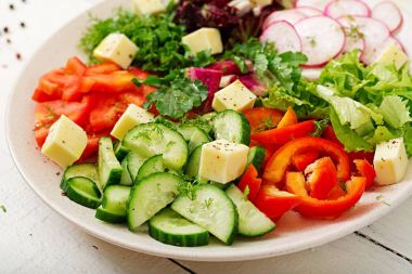 Ahşap masa üzerinde beyaz kase taze sebze ve yeşil ot salatası mix 