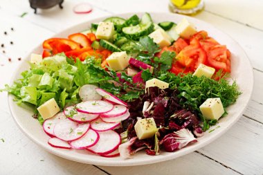 Ahşap masa üzerinde beyaz kase taze sebze ve yeşil ot salatası mix 