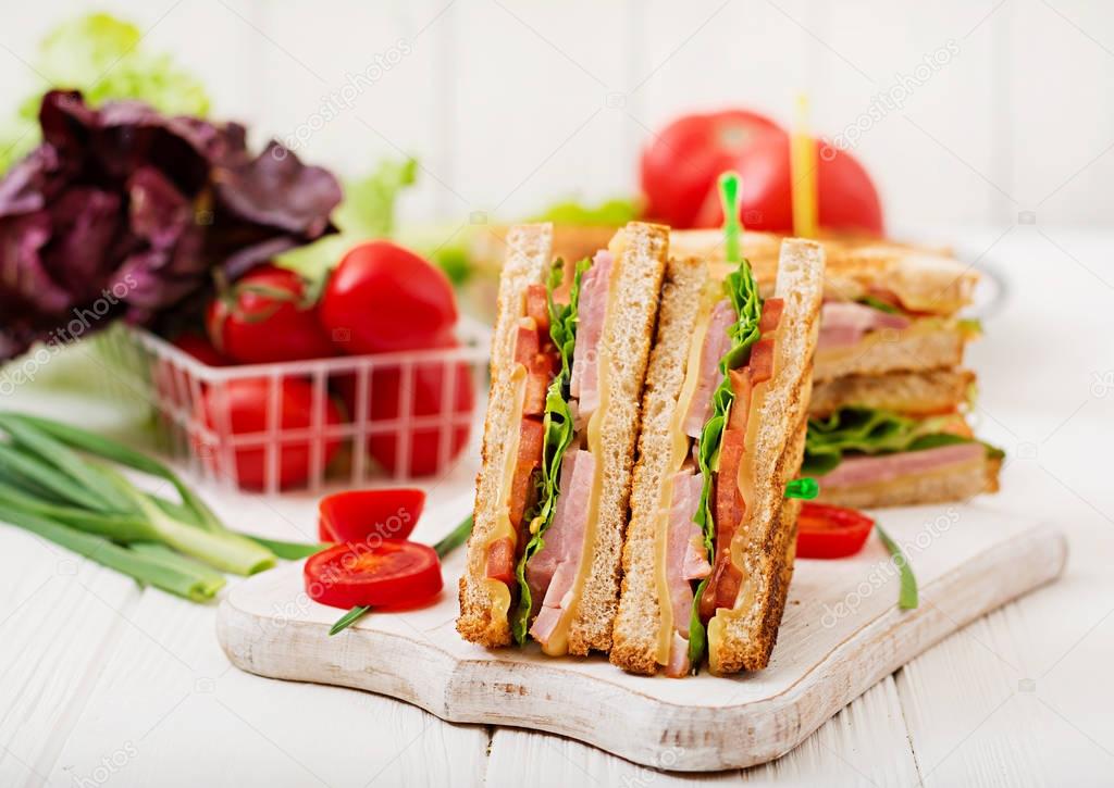 club sandwiches with ham and cheese on wooden cutting board 
