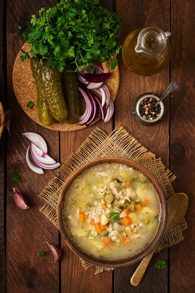 Soup with pickled cucumbers and pearl barley - rassolnik on a wooden background. Top view. — Stock Image Soup Pickled Cucumbers Pearl Barley Rassolnik Wooden Background Top View Stock Photo