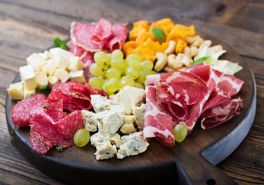 Meze tabağı pastırma, Kuru et, sosis, mavi peynir ve ahşap arka plan üzerinde üzüm ile catering.