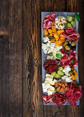 Meze tabağı pastırma, Kuru et, sosis, mavi peynir ve ahşap arka plan üzerinde üzüm yemek. Üstten Görünüm