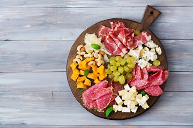 Meze tabağı pastırma, Kuru et, sosis, mavi peynir ve ahşap arka plan üzerinde üzüm yemek. Üstten Görünüm