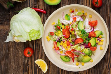 İştah açıcı vegan salata domates, avokado, Mısır, kırmızı soğan ve marul yaprakları. Lezzetli vejetaryen yemekleri. Sağlıklı vegan gıda. Vejetaryen salata. Üstten Görünüm
