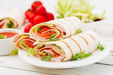 Jambon, peynir ve domates Beyaz ahşap zemin üzerinde tortilla sarın