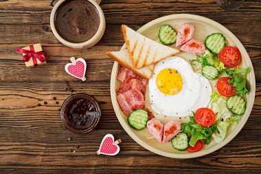 Sevgililer Günü ' - bir kalp, tost, sosis, pastırma ve taze sebze şeklinde kızarmış yumurta kahvaltı. İngiliz kahvaltısı. Bir fincan kahve. Üstten Görünüm