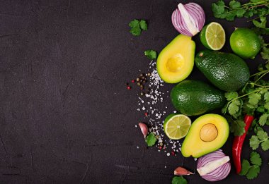 Guacamole sosu malzemeler - avokado, soğan, biber biber, sarımsak, kişniş, siyah arka plan üzerine kireç. Üstten Görünüm