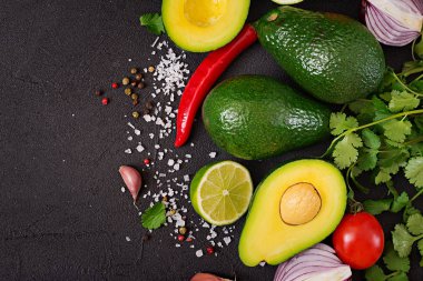 Guacamole sosu malzemeler - avokado, domates, soğan, biber biber, sarımsak, kişniş, siyah arka plan üzerine kireç. Üstten Görünüm