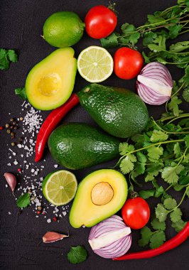 Guacamole sosu malzemeler - avokado, domates, soğan, biber biber, sarımsak, kişniş, siyah arka plan üzerine kireç. Üstten Görünüm
