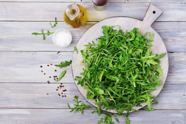 Roka bir kase taze yaprakların hafif ahşap arka plan üzerinde. Düz yatıyordu. Üstten Görünüm