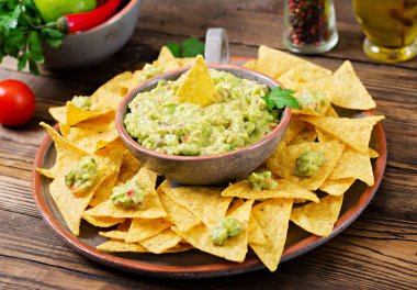 Guacamole avokado, limon, domates, soğan ve kişniş, nachos ile servis edilir.