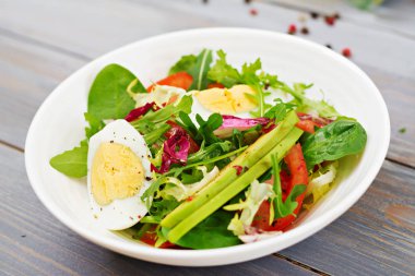 Lezzetli ve hafif salata, domates, yumurta ve bir karışım marul yaprakları. Sağlıklı kahvaltı.