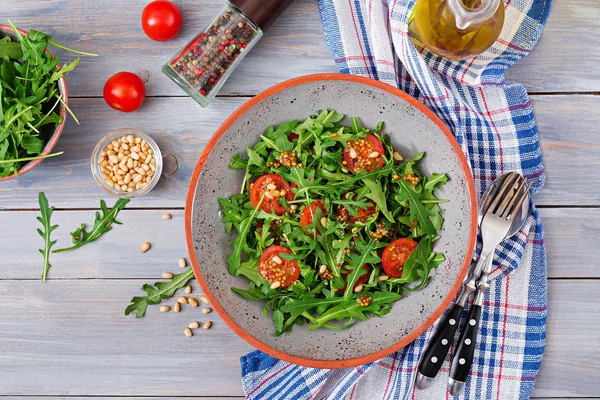 Dietary menu. Vegan cuisine. Healthy salad with arugula, tomatoes and pine nuts. Flat lay. Top view