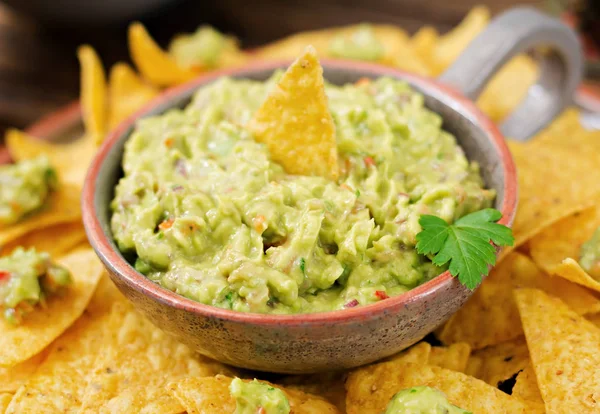Guacamole avokado, limon, domates, soğan ve kişniş, nachos ile servis edilir.