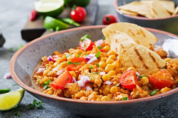 Chili con carne with turkey, chickpeas served with nachos. Chili with meat, nachos, lime, hot pepper. Mexican / Texas traditional food