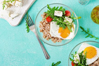 Yumurta, beyaz peynir, roka, domates ve buğday lapası ışık arka plan üzerinde sağlıklı kahvaltı.