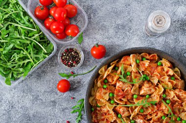 Farfalle makarna tavuk fileto, domates sosu ve yeşil bezelye ile. Ev yapımı yemek. İtalyan mutfağı. Düz yatıyordu. Yemek menüsü. Üstten Görünüm