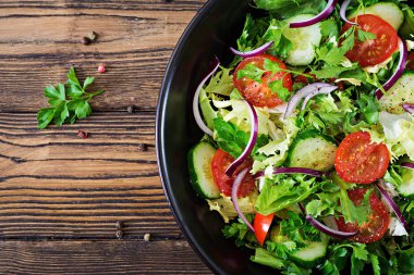 Yukarıdan vejetaryen salata domates, salatalık, kırmızı soğan ve marul yaprakları. Sağlıklı yaz vitamini menü. Vegan sebze gıda. Yemek Masası. Düz yatıyordu