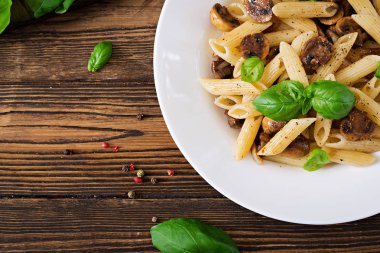 Vejetaryen sebze makarna penne ahşap masa üzerinde beyaz kase mantar ile yakın çekim fotoğraf. Vegan gıda.
