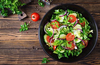 Yukarıdan vejetaryen salata domates, salatalık, kırmızı soğan ve marul yaprakları. Sağlıklı yaz vitamini menü. Vegan sebze gıda. Yemek Masası. Düz yatıyordu