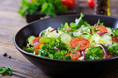 Domates, salatalık, kırmızı soğan ve marul salatası bırakır. Sağlıklı yaz vitamini menü. Vegan sebze gıda. Vejetaryen yemek masası.