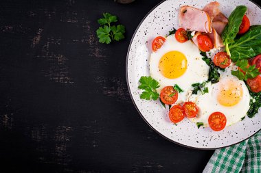 Keto diyet yemekli tabak. Yağda yumurta, jambon, ıspanak ve domates. Keto, paleo kahvaltısı. Üst görünüm, alanı kopyala