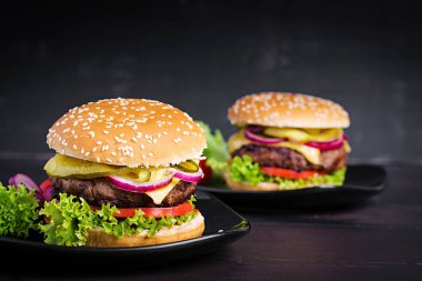Büyük sandviç - hamburgerli biftek, domates, peynir, salatalık turşusu ve kırmızı soğanlı.