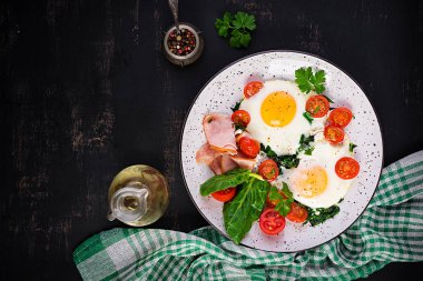 Keto diyet yemekli tabak. Yağda yumurta, jambon, ıspanak ve domates. Keto, paleo kahvaltısı. Üst görünüm, alanı kopyala