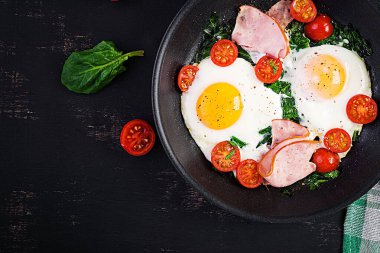 Keto diyet yemekli tabak. Yağda yumurta, jambon, ıspanak ve domates. Keto, paleo kahvaltısı. Üst görünüm, alanı kopyala
